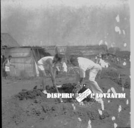 Dua orang lelaki sibuk menggali tanah dalm  bhakti dalam rangka memperingati hari  sumpah pemuda,...